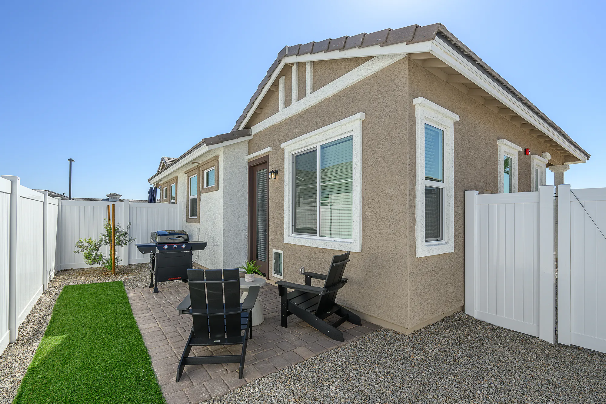 Fenced backyard with a paved patio and narrow green strip.